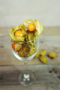 美丽和优雅的宏观特写镜头许多橙色美味的水果命名酸浆从秘鲁，南美洲，在一个水晶玻璃在木桌
