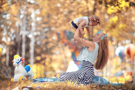 妈妈抱女儿摄影照片_妈妈抱着女儿在她的怀里秋天的照片在黄色公园
