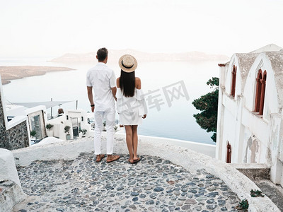 欧洲小镇摄影照片_白色欧洲小镇幸福的年轻夫妇的户外生活照片。走在圣托里尼岛上