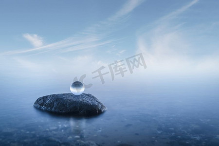 水晶球在一个有雾的海景与平静的蓝色水域岩石