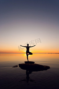 全民大健康摄影照片_高加索健身妇女练习瑜伽在海滩在日落。高加索健身妇女练习瑜伽