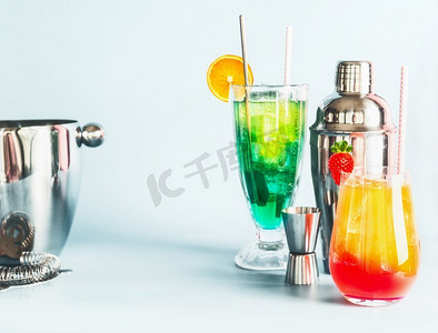 竖纹长虹玻璃摄影照片_各种五颜六色的长饮料和鸡尾酒酒吧工具在浅蓝色背景，复制空间夏季酒精饮料