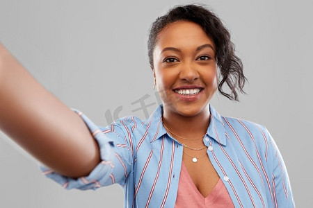 灰色人物照片背景摄影照片_人物概念-快乐的非裔美国年轻女子在灰色背景上自拍。快乐的非裔美国女性自拍
