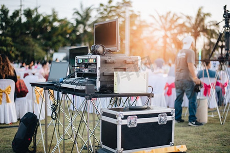 户外音乐会摄影照片_DJ混合均衡器在户外音乐派对节与派对餐桌。娱乐和活动组织者的概念。音乐会和音乐主题