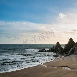 Westcombe海滩美丽的日落风景图象在德文郡英格兰与锯齿状岩石在海滩和惊人的云形成