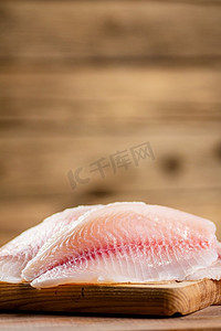 白色照片摄影照片_将新鲜的鱼片放在切菜板上。背景是木制的。高质量的照片。将新鲜的鱼片放在切菜板上。