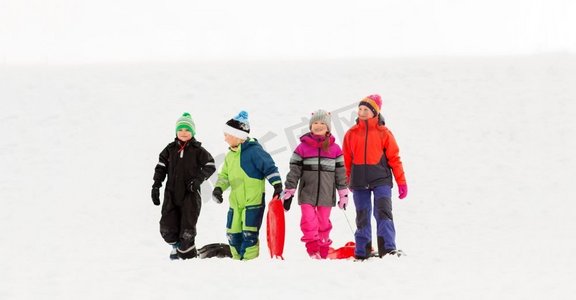 童年，雪橇和季节概念—一群快乐的小孩子在冬天雪橇。快乐的小孩子与雪橇在冬天