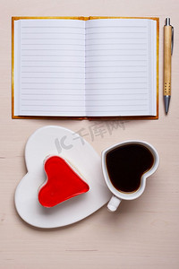咖啡杯果冻蛋糕，心形和纸质空白笔记本，桌面上有钢笔，俯视文本空间