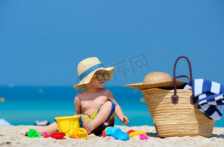 两岁的蹒跚学步的男孩在海滩上玩沙滩玩具 
