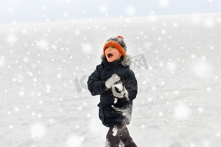 冬天小男孩摄影照片_童年，休闲，季节概念-快乐的小男孩在冬天玩雪。快乐的小男孩在冬天玩雪