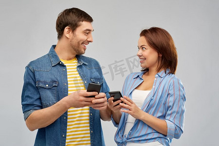 技术和人的概念—愉快的夫妇与智能手机谈话在灰色背景。幸福的夫妇与智能手机交谈