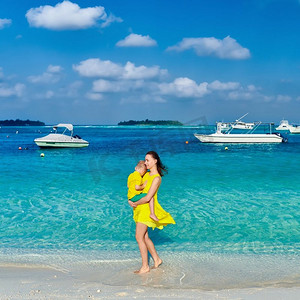 妈妈陪宝宝摄影照片_三岁的小男孩和妈妈一起在海滩上。暑假在马尔代夫度假。