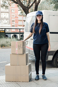 肖像年轻女快递员站在堆叠的纸箱里