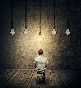 创造性的想法概念与一个人坐在一个黑暗的房间与悬挂灯泡和一个发光超过头。象征聪明的人有想法