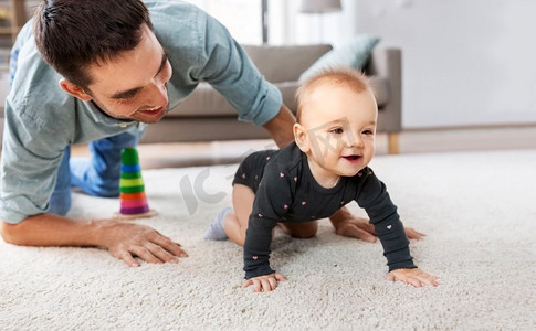 家庭，父亲和为人父母的概念—快乐的小女婴与父亲在家里爬在地板上。快乐的小女婴与父亲在家里