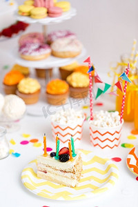 食物，庆祝和节日的概念—生日聚会上的蛋糕和蜡烛。生日聚会上盘子里的一块蛋糕