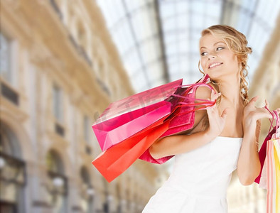 销售和人物--商场背景下，拿着五颜六色购物袋的女人。购物中心背景上拿着购物袋的女人