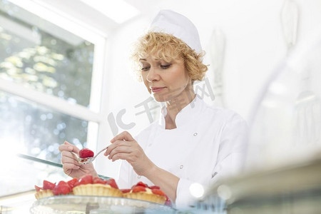 自信成熟的厨师在餐厅安排新鲜的草莓馅饼