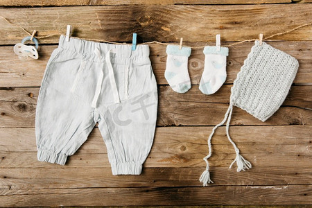 夹绳摄影照片_婴儿裤袜头饰安抚奶嘴挂晾衣绳与晒衣夹贴在木墙上