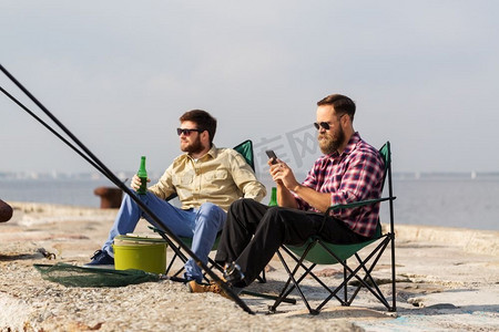 休闲和人的概念—男性朋友与智能手机钓鱼和喝啤酒。朋友与智能手机钓鱼和喝啤酒