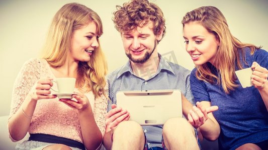 朋友在平板电脑上浏览互联网。年轻人男人男人和女人女孩在家里放松。朋友放松浏览平板电脑上的互联网。
