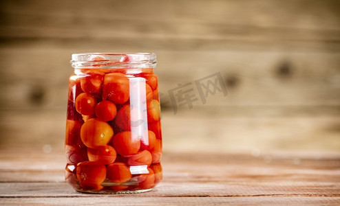 在玻璃罐里腌熟西红柿。在一个木制的背景。高质量的照片。在玻璃罐里腌熟西红柿。 