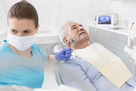 中年成人牙医与设备治疗老年病人在诊所