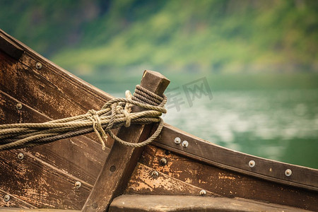 古船素材摄影照片_大自然峡湾岸边户外的旧木制维京船的一部分。旧木制海盗船特写的一部分