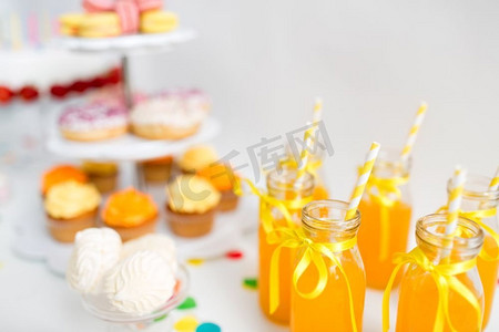 生日派对和饮料概念—玻璃瓶橙汁与纸吸管放在桌子上。玻璃瓶橙汁与纸吸管