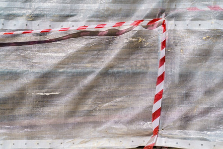 安全条纹摄影照片_建筑工地的危险警告胶带。红色和白色的条纹轻织物。建筑工地的危险警告带