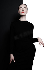 时尚艺术工作室象在几何黑白背景的优雅的妇女。用红色唇膏专业化妆。时尚的经典连衣裙。