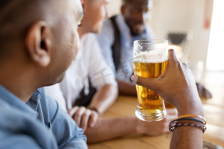 休闲和饮品概念-男性朋友在酒吧或酒吧喝啤酒。在酒吧或酒吧喝啤酒的男性朋友
