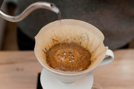 量水的温度摄影照片_高角度男咖啡师倒热水咖啡滤清器