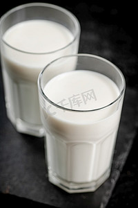 石板上的一杯新鲜牛奶。在黑色背景上。高质量的照片。石板上的一杯新鲜牛奶。