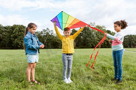 风筝玩具摄影照片_童年，休闲和人的概念—一群快乐的孩子在公园玩风筝。快乐的孩子与风筝玩在公园