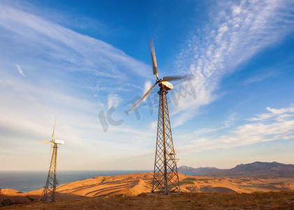 日落时分，山上有风力涡轮机发电的工业景观。