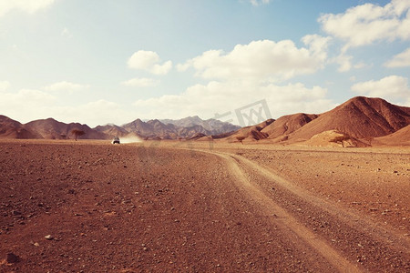 车在沙漠摄影照片_在非洲的野生动物和极端旅行。干旱山地景观与灰尘在越野车探险的道路。