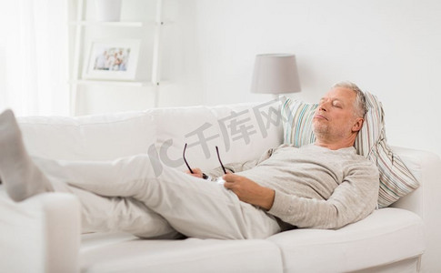 舒适睡眠摄影照片_老年，休息，舒适和人的概念—老年人睡在沙发上在家里。老年人睡在沙发上在家里