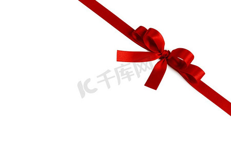 红缎摄影照片_闪亮的红缎丝带和弓隔绝在白色背景。节日礼物的概念。闪亮的红缎丝带蝴蝶结