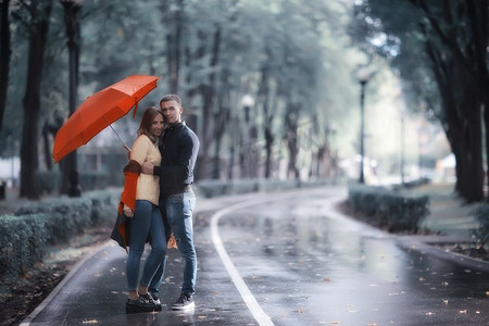 雨在秋天公园/年轻的25岁夫妇男人和女人走在伞下在潮湿的雨天，走十月情人