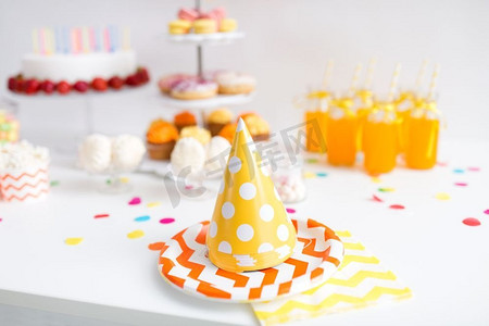 橙色生日摄影照片_生日和节日概念—派对帽，食物和饮料上桌。生日派对帽，食物和饮料