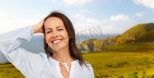人和休闲的概念-快乐的微笑的女人在加利福尼亚州的大苏尔海岸背景。加利福尼亚州大苏尔海岸上微笑的女人