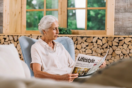 关闭妇女坐在椅子阅读报纸
