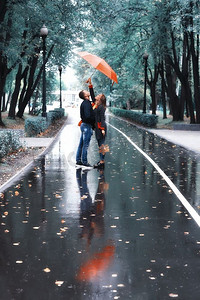 一男一女打着伞在公园里散步