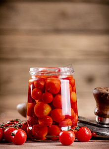 在玻璃罐里腌熟西红柿。在一个木制的背景。高质量的照片。在玻璃罐里腌熟西红柿。 