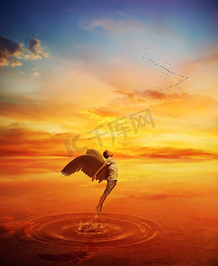 飞纹摄影照片_超现实主义的图像，天使试图从湖水中跳下来，飞走。在天堂日落背景的伟大精神逃脱。