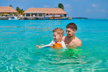 三岁的小男孩和爸爸一起学游泳。暑假在马尔代夫度假。