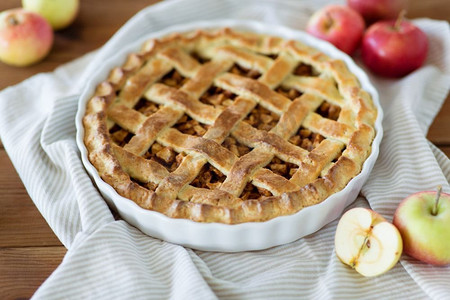 食物，烹饪和糕点的概念-特写苹果馅饼在厨房毛巾上的烘焙模具。毛巾上的苹果派在烘焙模子里的特写