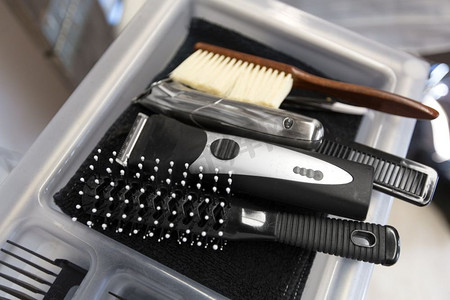 修护摄影照片_理发工具、美容和美发概念-理发店的梳子、修剪器和盘中梳子。美发沙龙的刷子、修剪器和梳子在托盘上