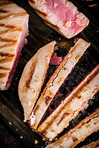 在切菜板上烤金枪鱼。在黑暗的背景下。高质量的照片。在切菜板上烤金枪鱼。